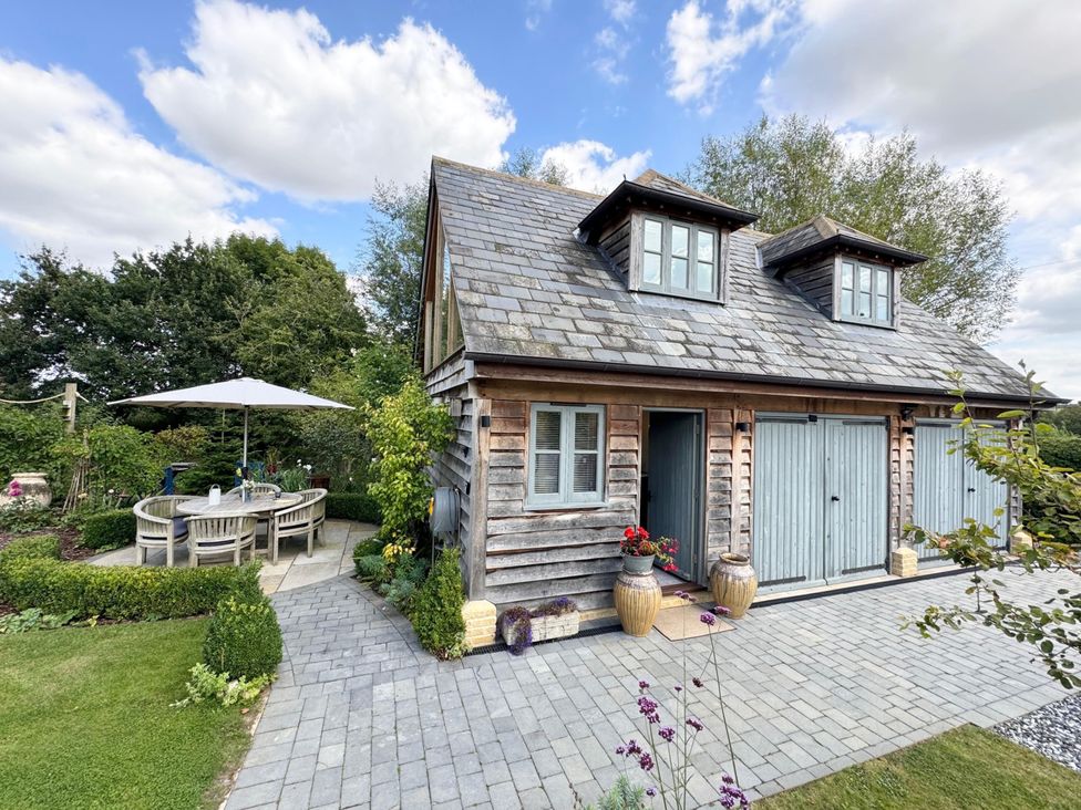 An outdoor space with a wooden building and seating area at Christmas Cottage in Shipston-on-Stour