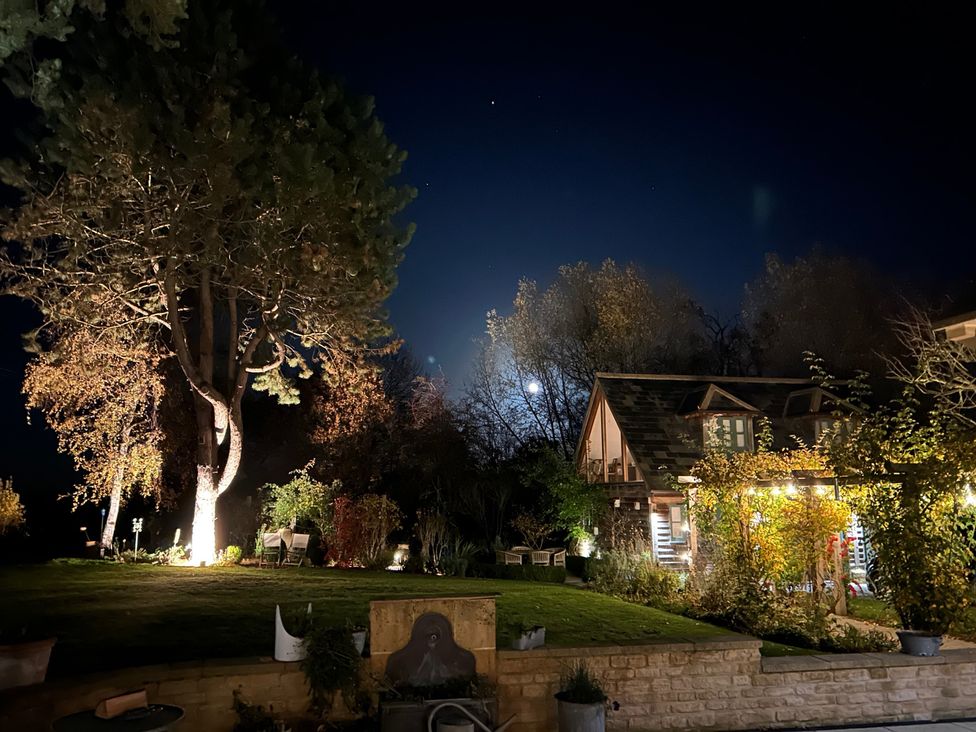 An outdoor garden with a house, trees and moonlight at Christmas Cottage in Shipston-on-Stour