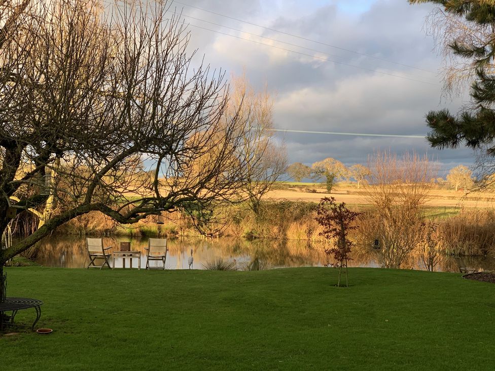 A garden with chairs and a table near a pond at Christmas Cottage in Shipston-on-Stour