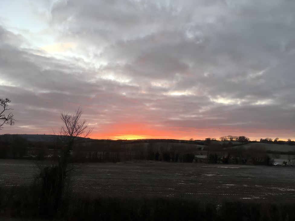 A sunset view over fields and trees at Christmas Cottage in Shipston-on-Stour