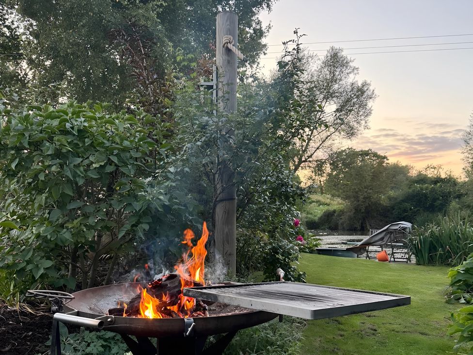A fire pit with flames in a garden at Christmas Cottage in Shipston-on-Stour