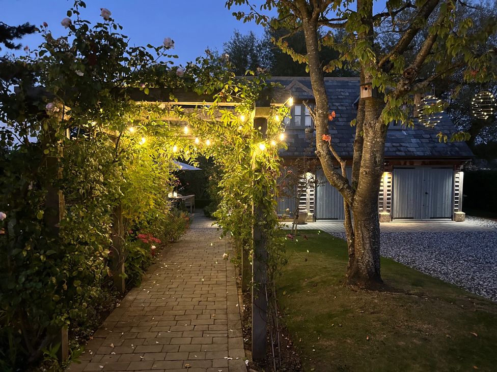 An outdoor pathway with lights and plants leading to a building at Christmas Cottage in Shipston-on-Stour