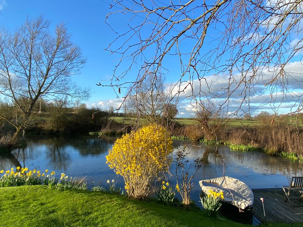 A view of a river with trees and flowers at Christmas Cottage in Shipston-on-Stour