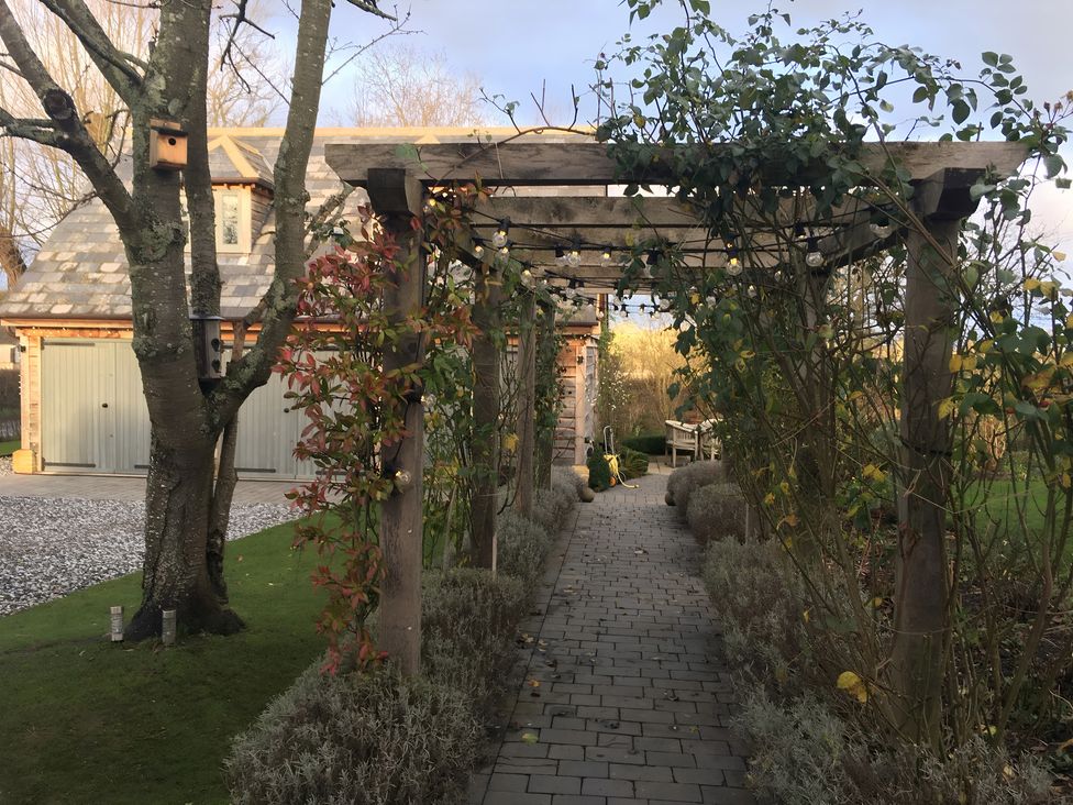 A pathway leading through a pergola in the garden at Christmas Cottage in Shipston-on-Stour