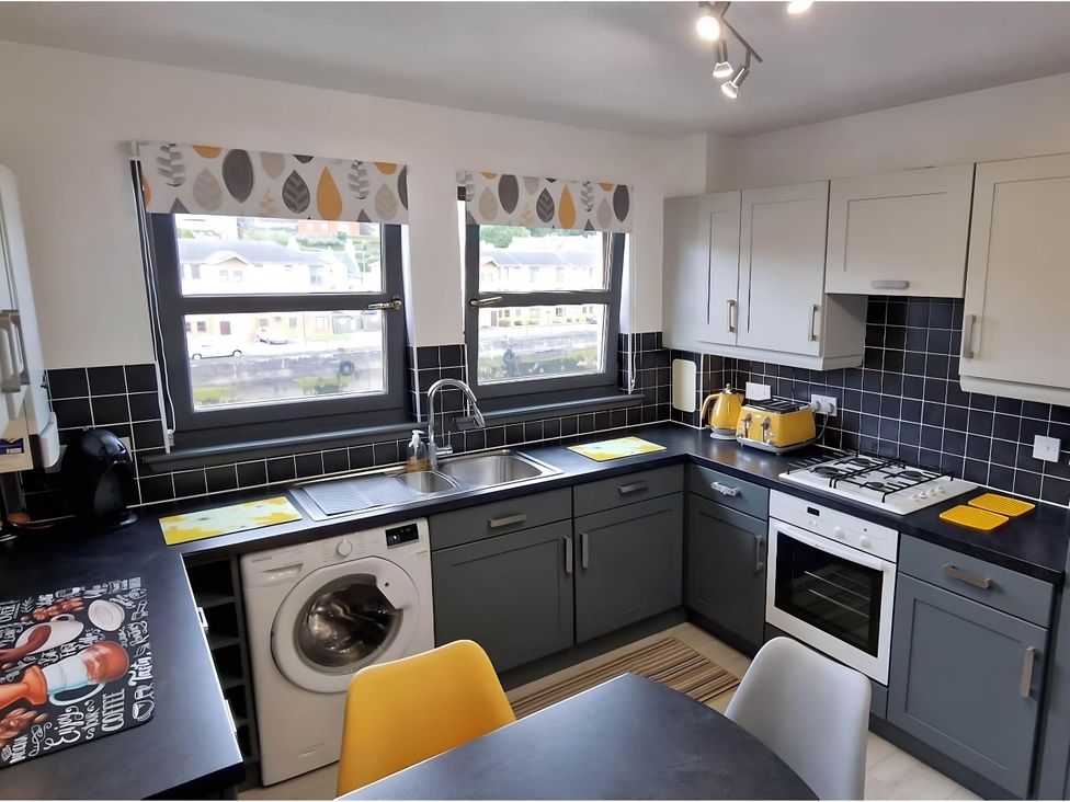 A kitchen with a sink, cooker, oven, and washing machine at 36 Deas Wharf in Kirkcaldy