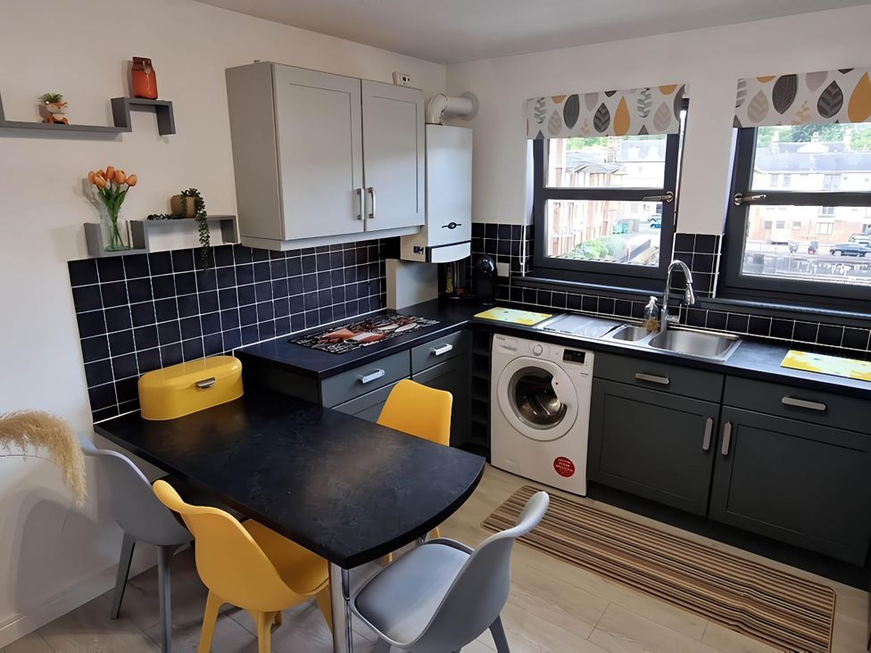 A kitchen with a stove, sink, and washing machine at 36 Deas Wharf, Kirkcaldy