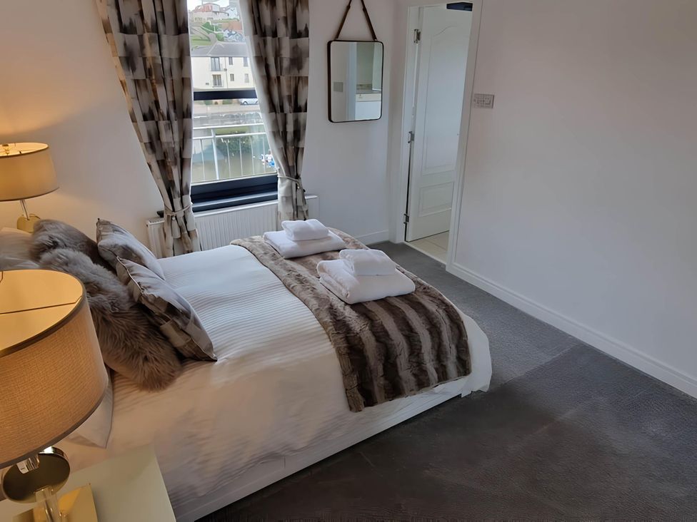 A bedroom with a bed, pillows, and a lamp at 36 Deas Wharf Kirkcaldy