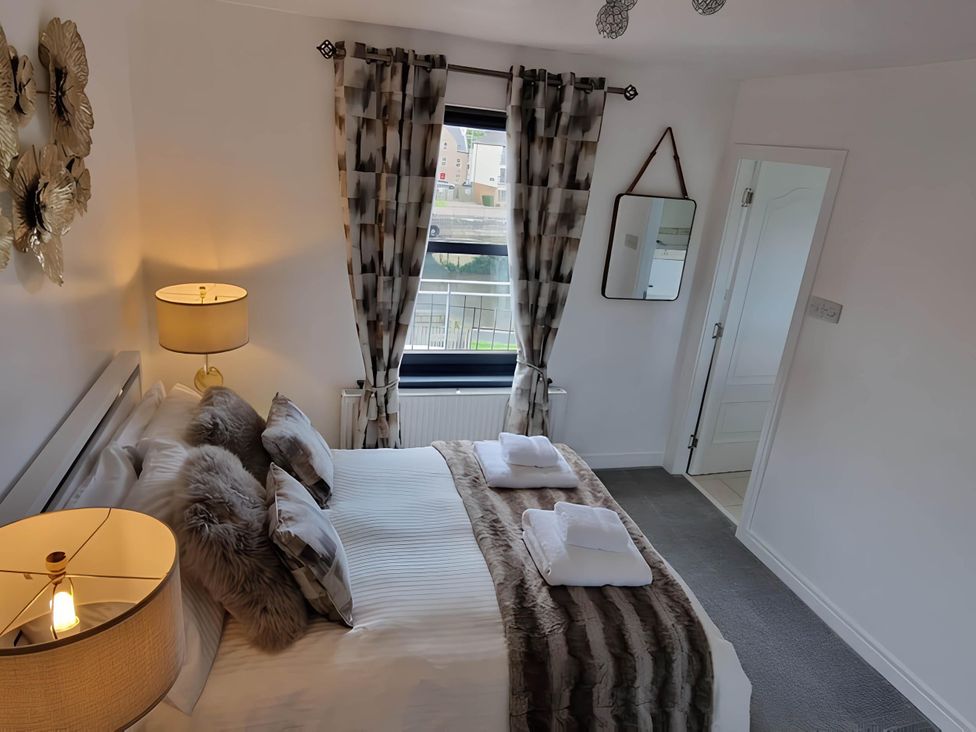 A bedroom with a bed and curtains at 36 Deas Wharf, Kirkcaldy