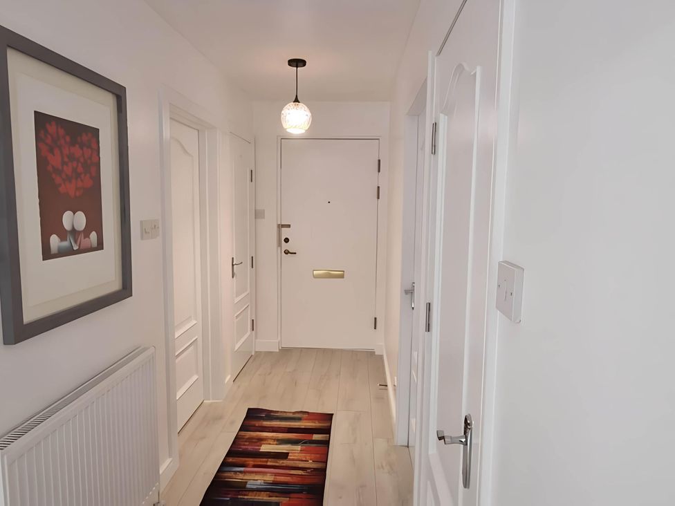 A hallway with a front door and artwork at 36 Deas Wharf in Kirkcaldy
