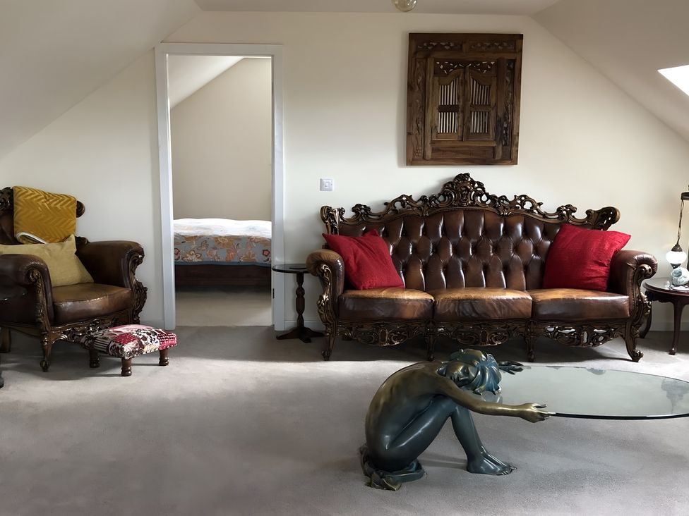 A living room with a sofa, armchair, and sculpture at Country Retreat Sleeps 2 Holyhead