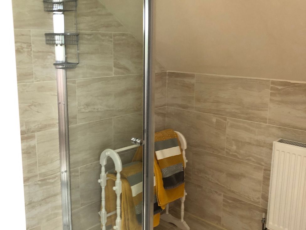 A bathroom with a shower and towels on a rack at Country Retreat Sleeps 2 Holyhead