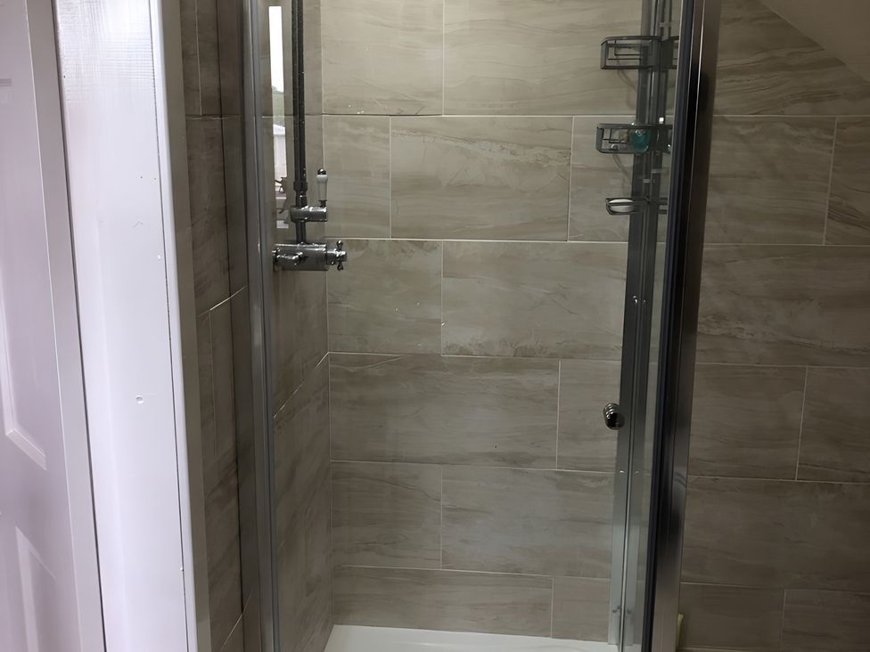 A shower stall with glass door and tile walls at Country Retreat Sleeps 2 Holyhead