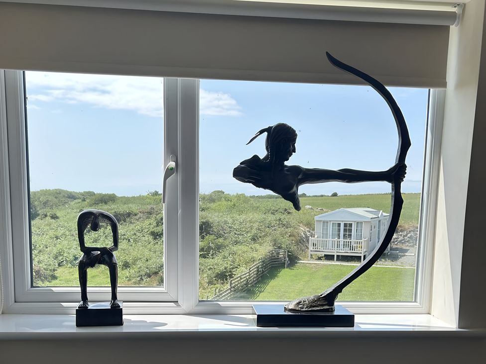 Two sculptures on a windowsill with a view of a garden at Country Retreat Sleeps 2 in Holyhead