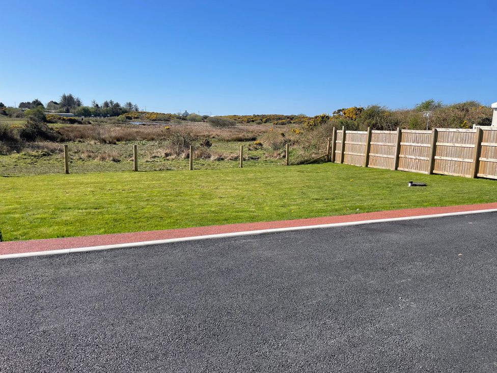 A grassy area with a fence and road at Country Retreat Sleeps 2 Holyhead