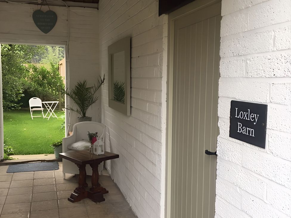 An entrance area with a table and a chair at Loxley Barn in Tring