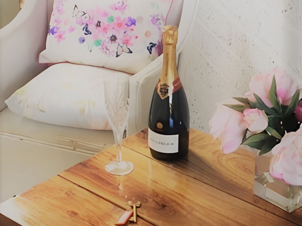 A living room with a champagne bottle and glass on a table at Loxley Barn in Tring