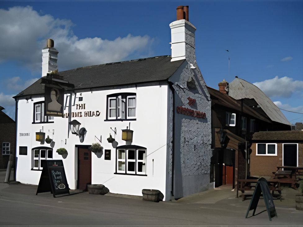 A pub building exterior with a sign and outdoor seating at Loxley Barn in Tring