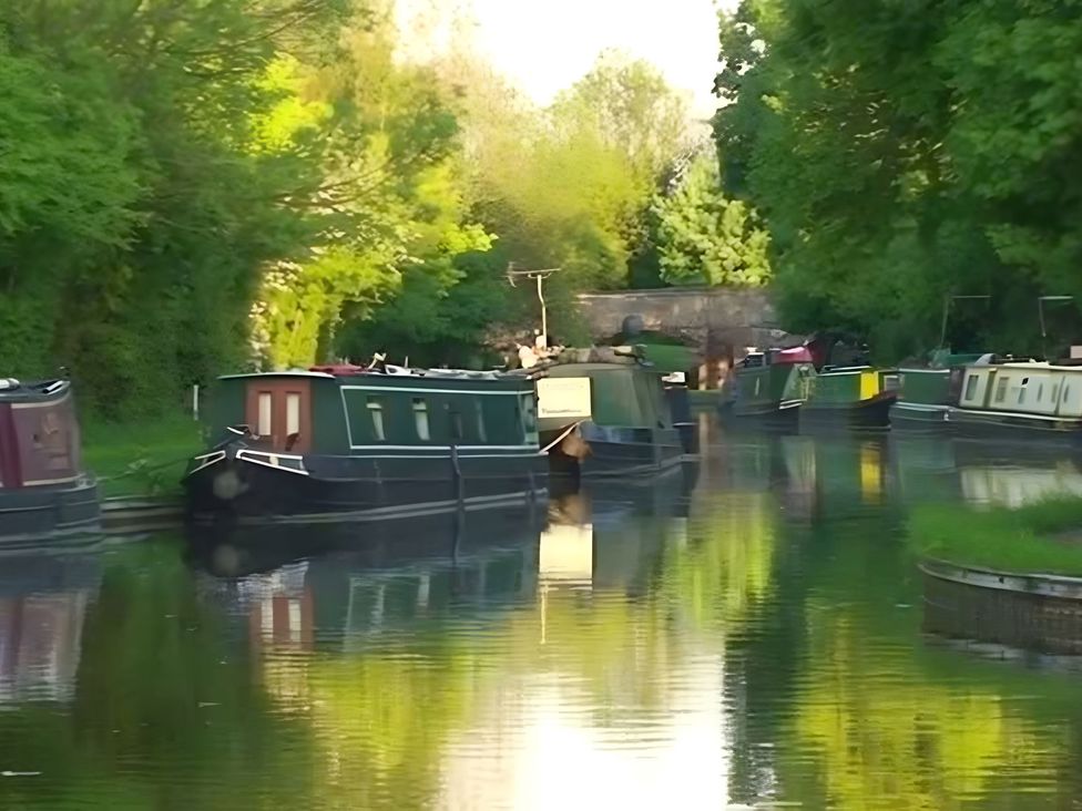 Narrowboats on a canal with trees in the background at Loxley Barn Tring