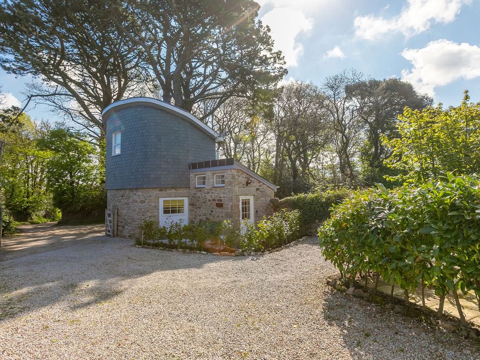A house with a gravel driveway surrounded by trees at The Old Well House Redruth