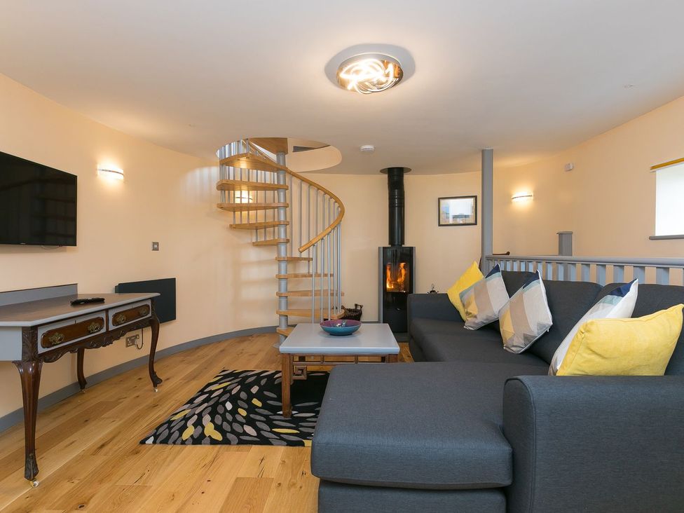 A living room with a spiral staircase and a fireplace at The Old Well House in Redruth