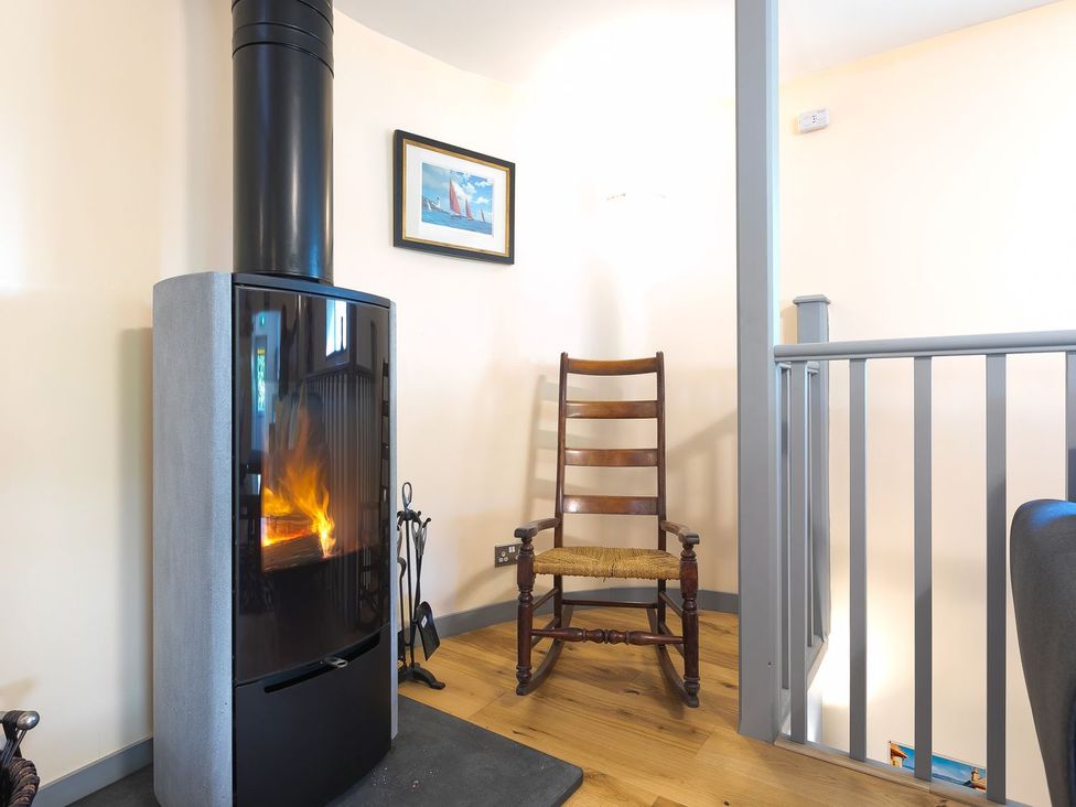 A living room with a stove and a rocking chair at The Old Well House Redruth