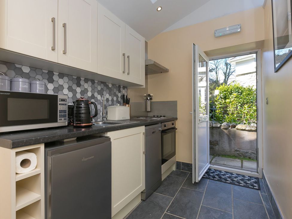 A kitchen with a microwave, kettle, sink, and stove at The Old Well House in Redruth
