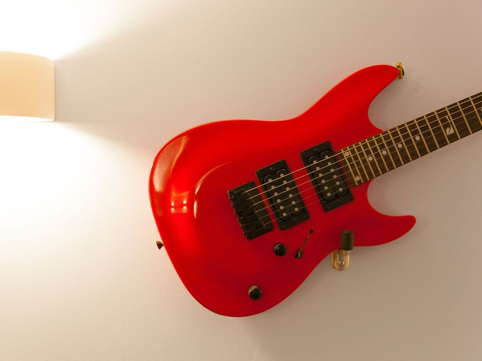 An electric guitar on a wall with a light fixture at The Old Well House in Redruth