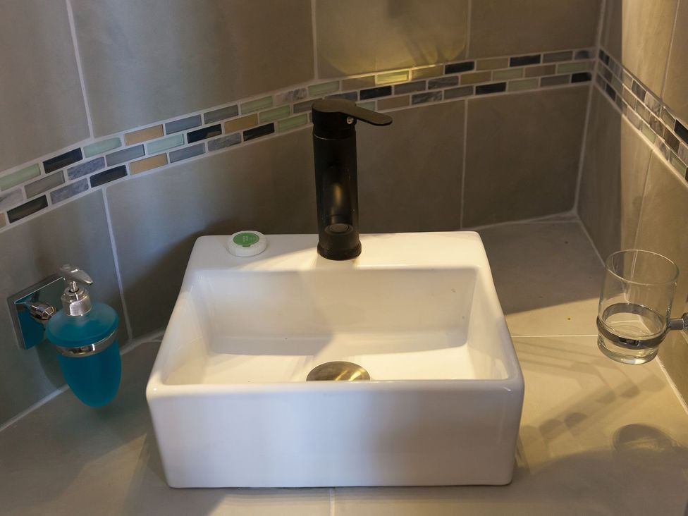A sink with tap and soap dispenser in a bathroom at The Old Well House Redruth