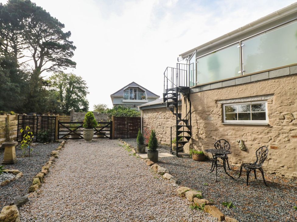 A garden with a gravel pathway and outdoor seating at The Old Well House in Redruth