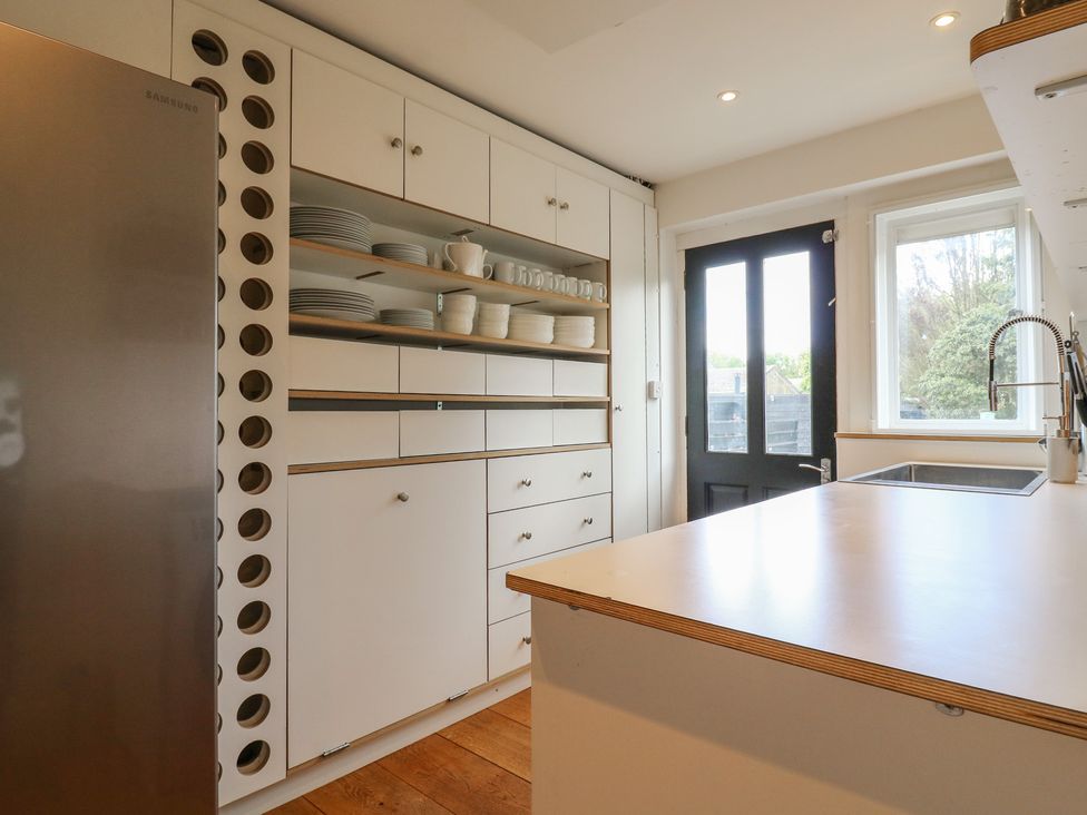 A kitchen with a refrigerator, shelves, and sink at Denmark House in Chatham, Kent