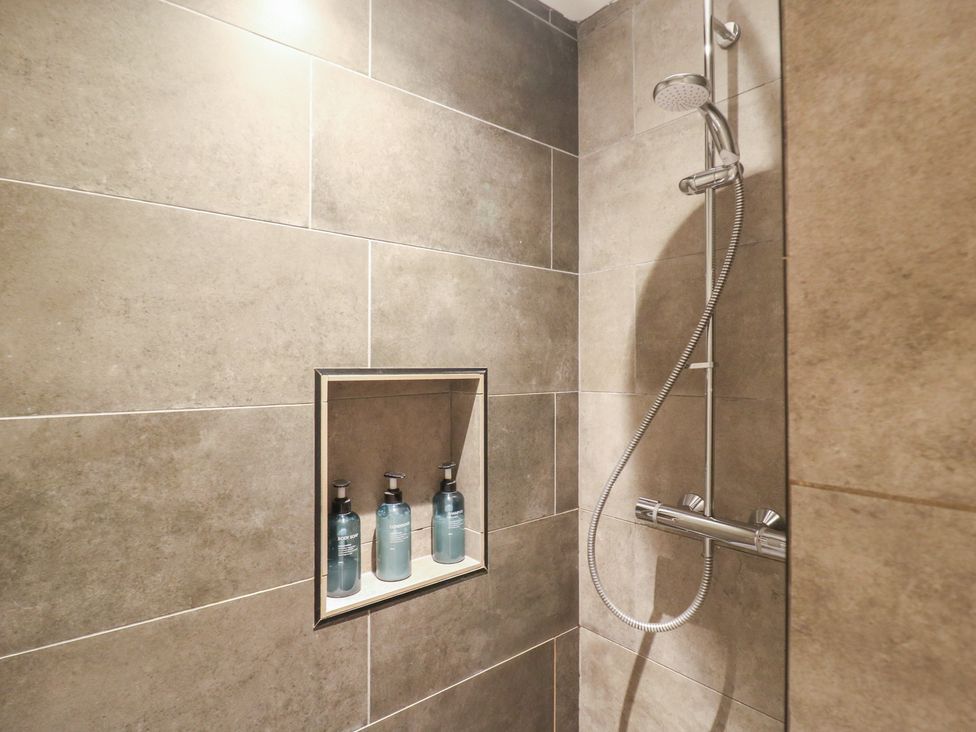 A shower with wall tiles and liquid soap bottles at Denmark House in Chatham, Kent