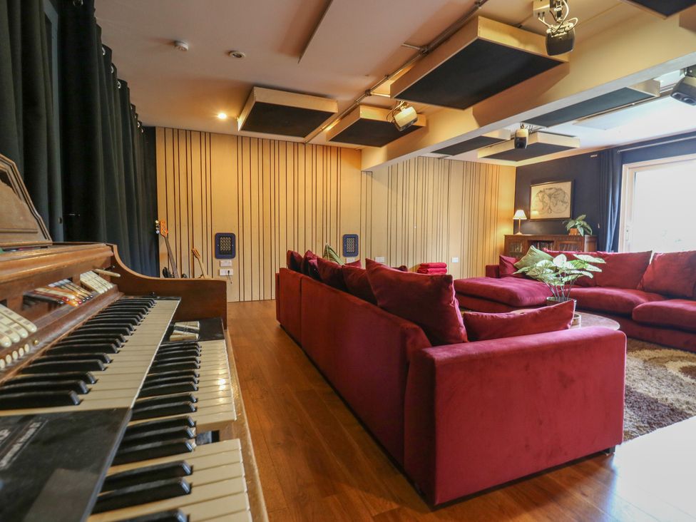 A living room with a piano and red sofas at Denmark House in Chatham, Kent