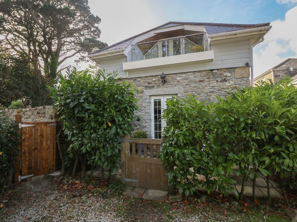 A stone building with a gate and greenery at Poppyfields Stable Redruth