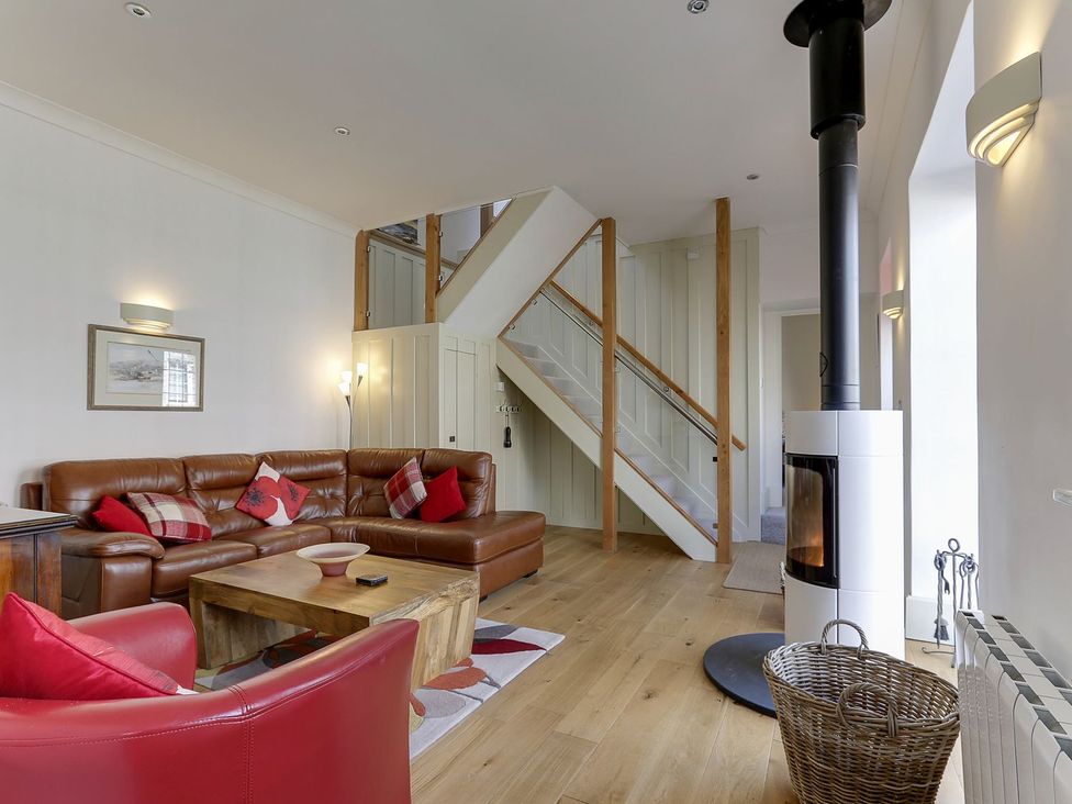 A living room with a sofa and a stove at Poppyfields Stable in Redruth