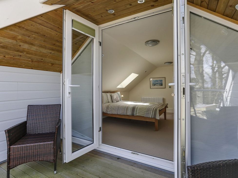 A bedroom with sliding doors and a chair at Poppyfields Stable Redruth