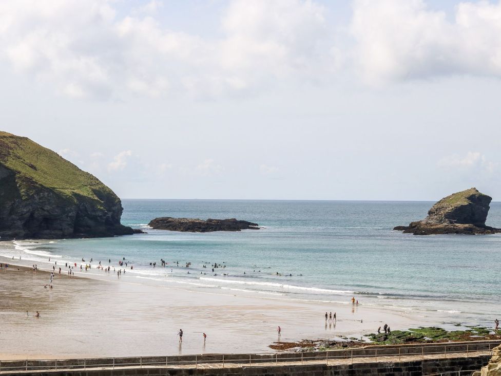 A beach with people walking and swimming near rocks at Poppyfields Stable Redruth