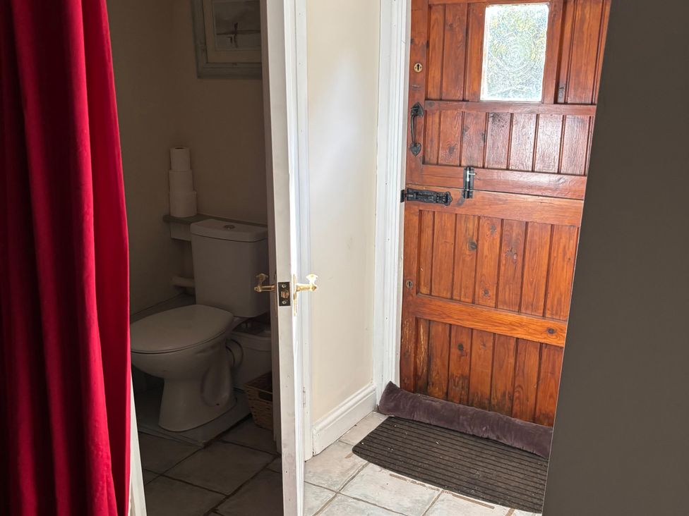 A bathroom with a toilet and a wooden door at 2 Bed Barn in Barroway Drove near Downham Market