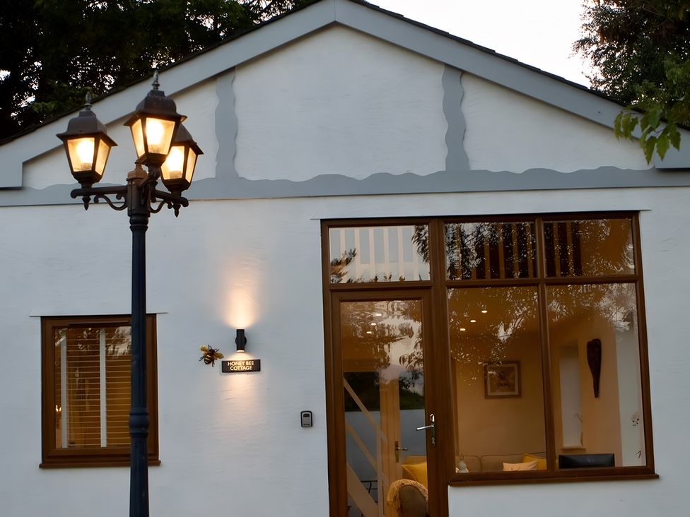 A cottage exterior with a lamp post and windows at Honey Bee Cottage in Welshpool
