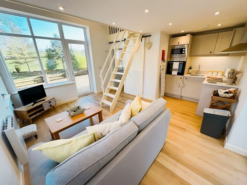 A living room with a sofa and staircase at Honey Bee Cottage Welshpool