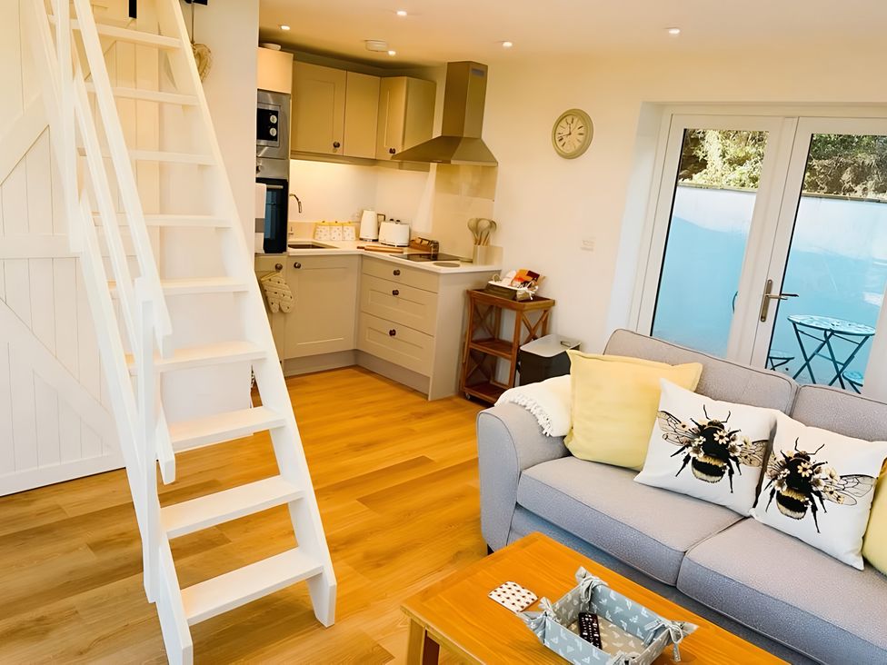 A living room with a staircase leading to a kitchen at Honey Bee Cottage in Welshpool