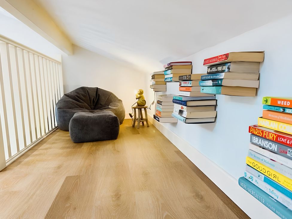 A reading nook with a bean bag chair and books on shelves at Honey Bee Cottage Welshpool
