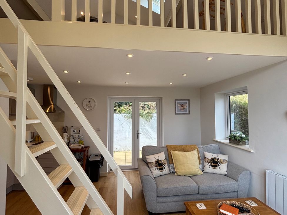 A living room with a staircase and kitchenette at Honey Bee Cottage in Welshpool
