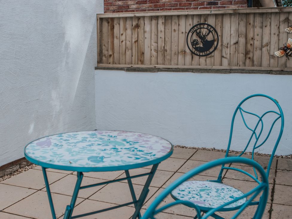An outdoor patio with a table and chair at Honey Bee Cottage in Welshpool