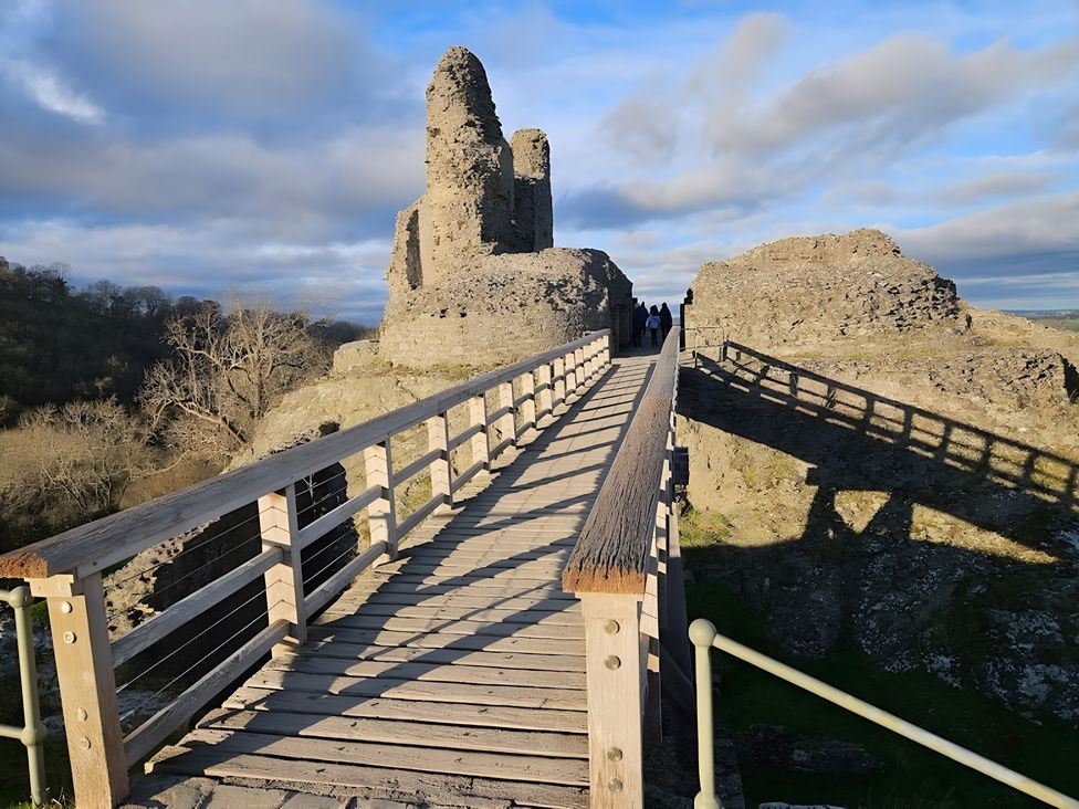 A bridge leading to castle ruins with people at Honey Bee Cottage in Welshpool