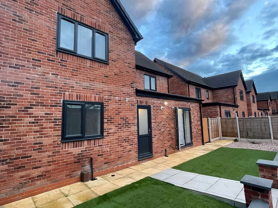 A backyard with brick wall and lawn at Citrine Suite in Stoke-on-Trent
