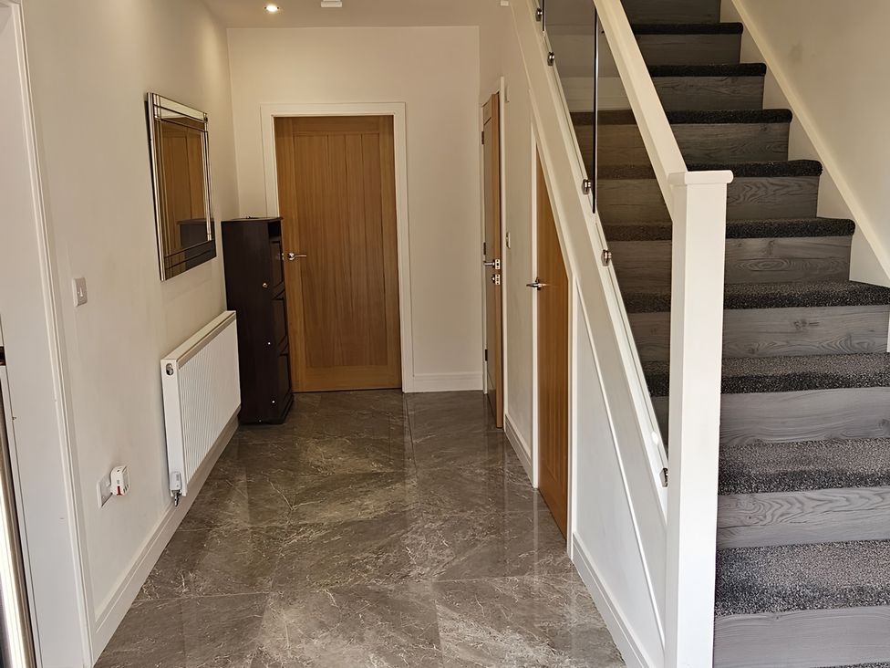 A hallway with a staircase and cabinet at Citrine Suite in Stoke-on-Trent