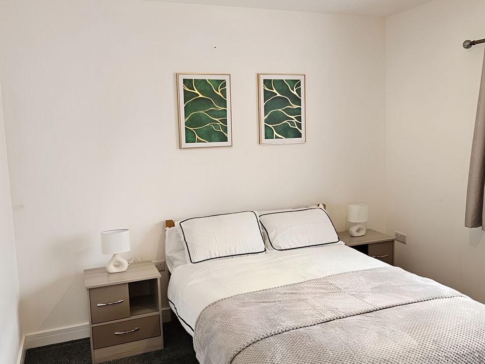 A bedroom with a bed and nightstands at Citrine Suite Stoke-on-Trent