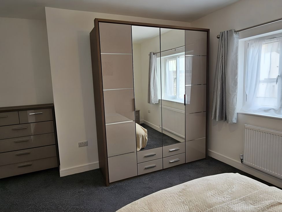 A bedroom with a wardrobe and chest of drawers at Citrine Suite in Stoke-on-Trent