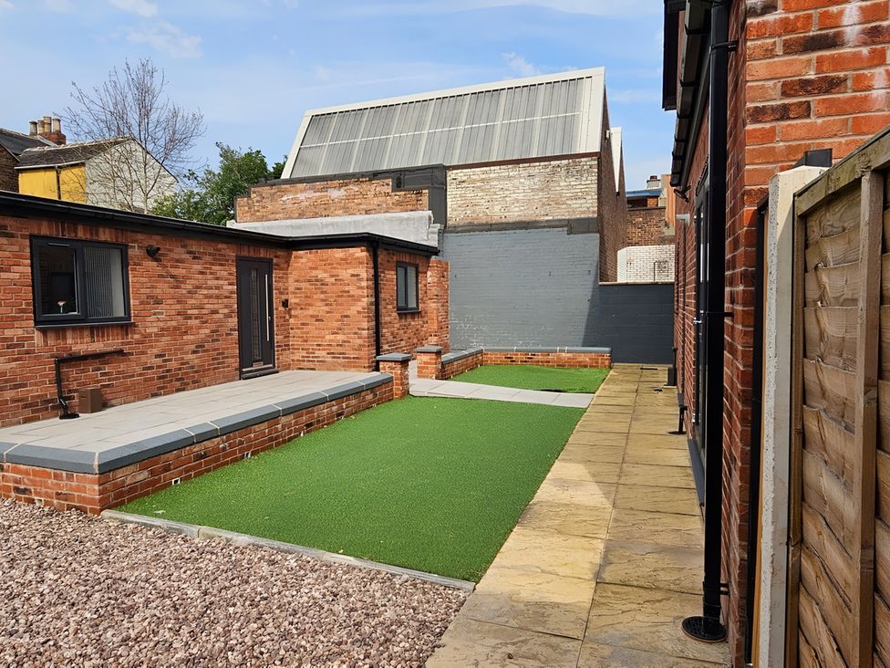 A garden with brick walls and patio at Citrine Suite in Stoke-on-Trent