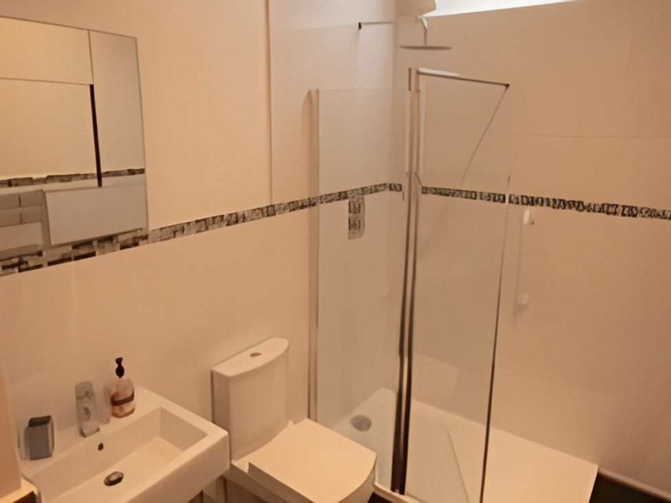 A bathroom with a shower and sink at 2nd Floor Apartment in Llandudno